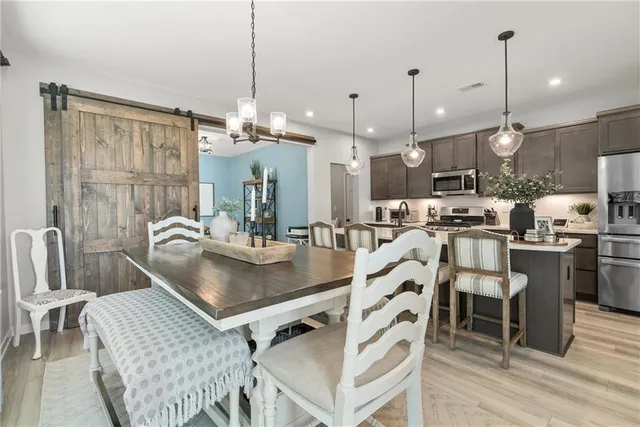 a kitchen with kitchen island a dining table chairs stainless steel appliances and cabinets