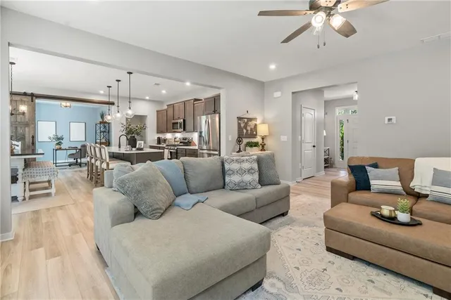 a living room with furniture kitchen view and a chandelier