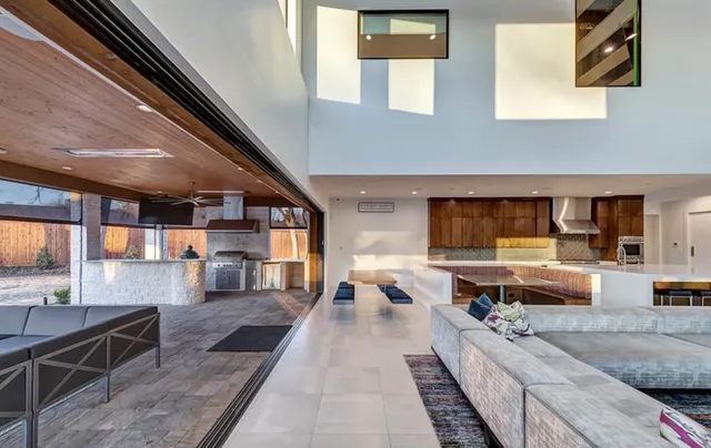 a large living room with stainless steel appliances furniture a rug and a large window