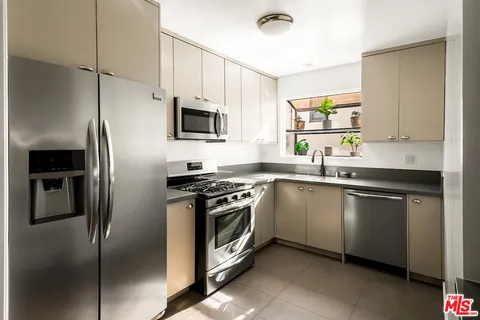 a kitchen with stainless steel appliances granite countertop a refrigerator a sink a stove a microwave a sink and dishwasher