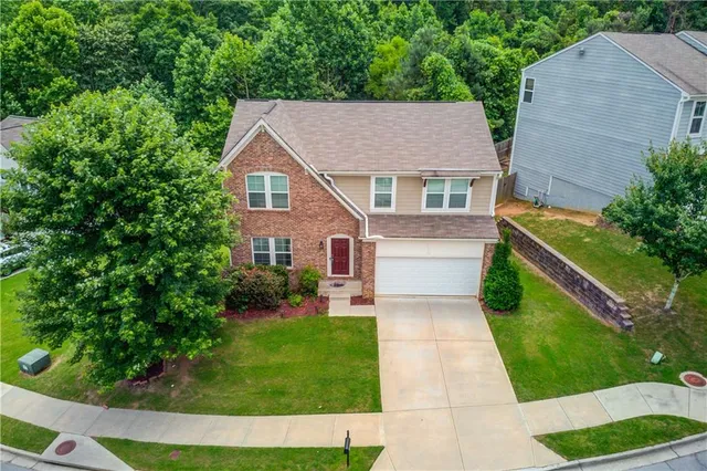 a aerial view of a house with a yard plants and large tree