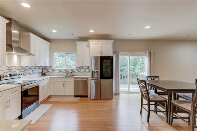 a kitchen with stainless steel appliances granite countertop wooden floor a large window a sink and a stove