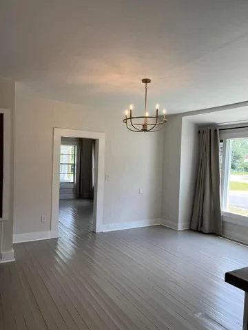 an empty room with wooden floor and window