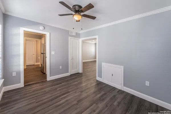 an empty room with wooden floor and ceiling fan