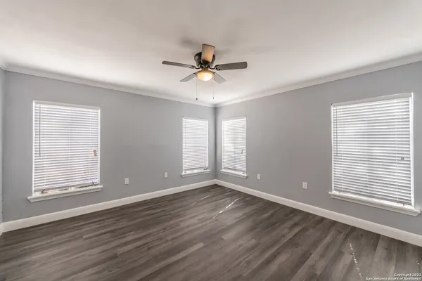 a view of an empty room with a window and wooden floor
