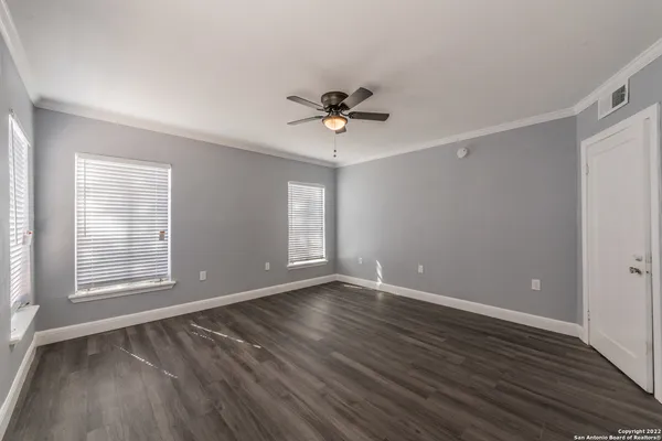 an empty room with wooden floor and windows