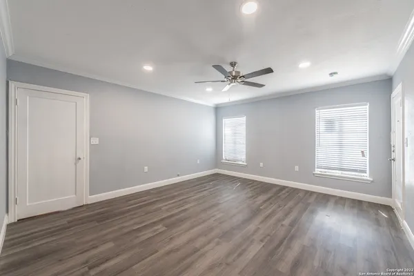 a view of an empty room with a window and wooden floor
