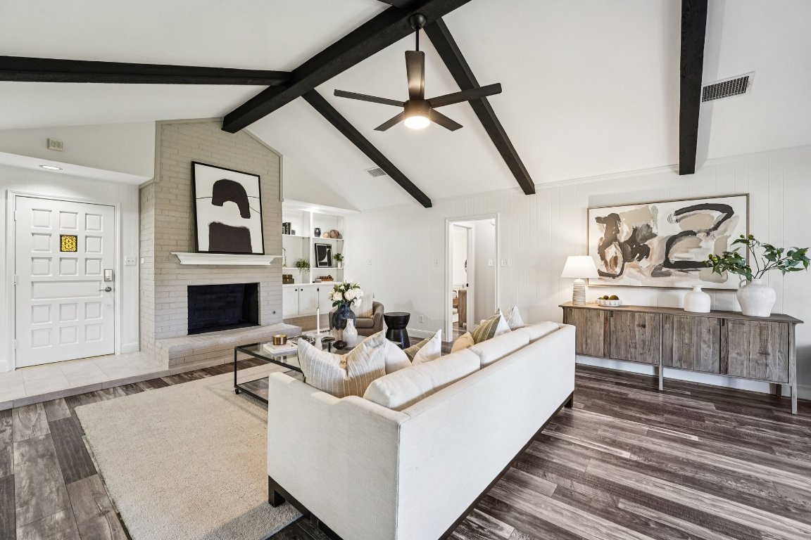 Living room featuring a brick fireplace, dark wood finished floors, and a ceiling fan