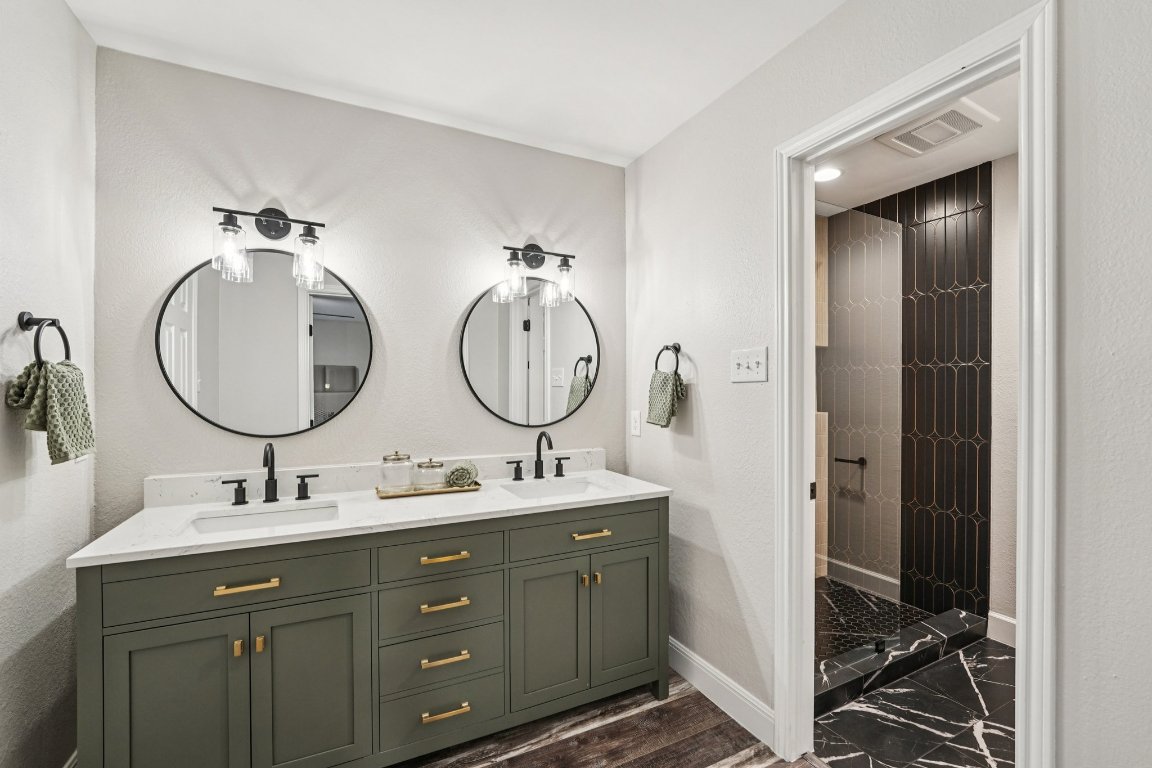 5307 Beckett Circle Austin, TX 78749 - Photo 19 of 29 Full bathroom featuring tiled shower, double vanity, a textured wall, and dark wood finished floors