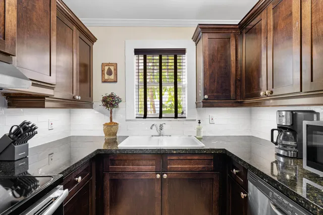 a kitchen with granite countertop cabinets a sink a stove and wooden cabinets