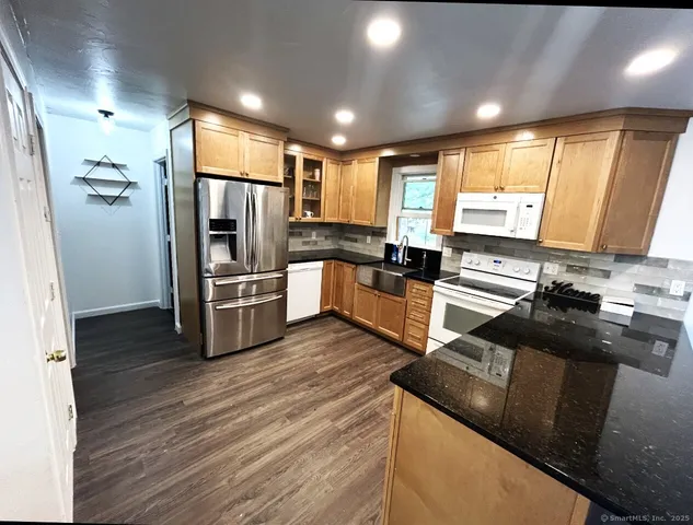 a kitchen with granite countertop a refrigerator and a stove top oven