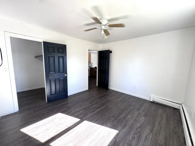 a view of an empty room with wooden floor and a ceiling fan