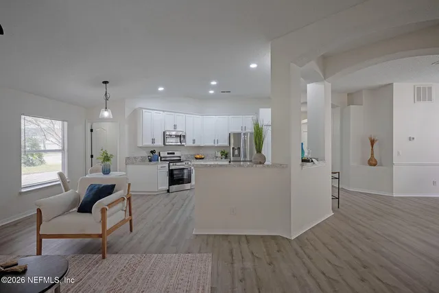 a kitchen with granite countertop a stove top oven a sink dishwasher a dining table and chairs with wooden floor