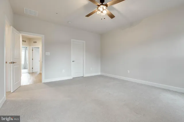 a view of an empty room and chandelier fan