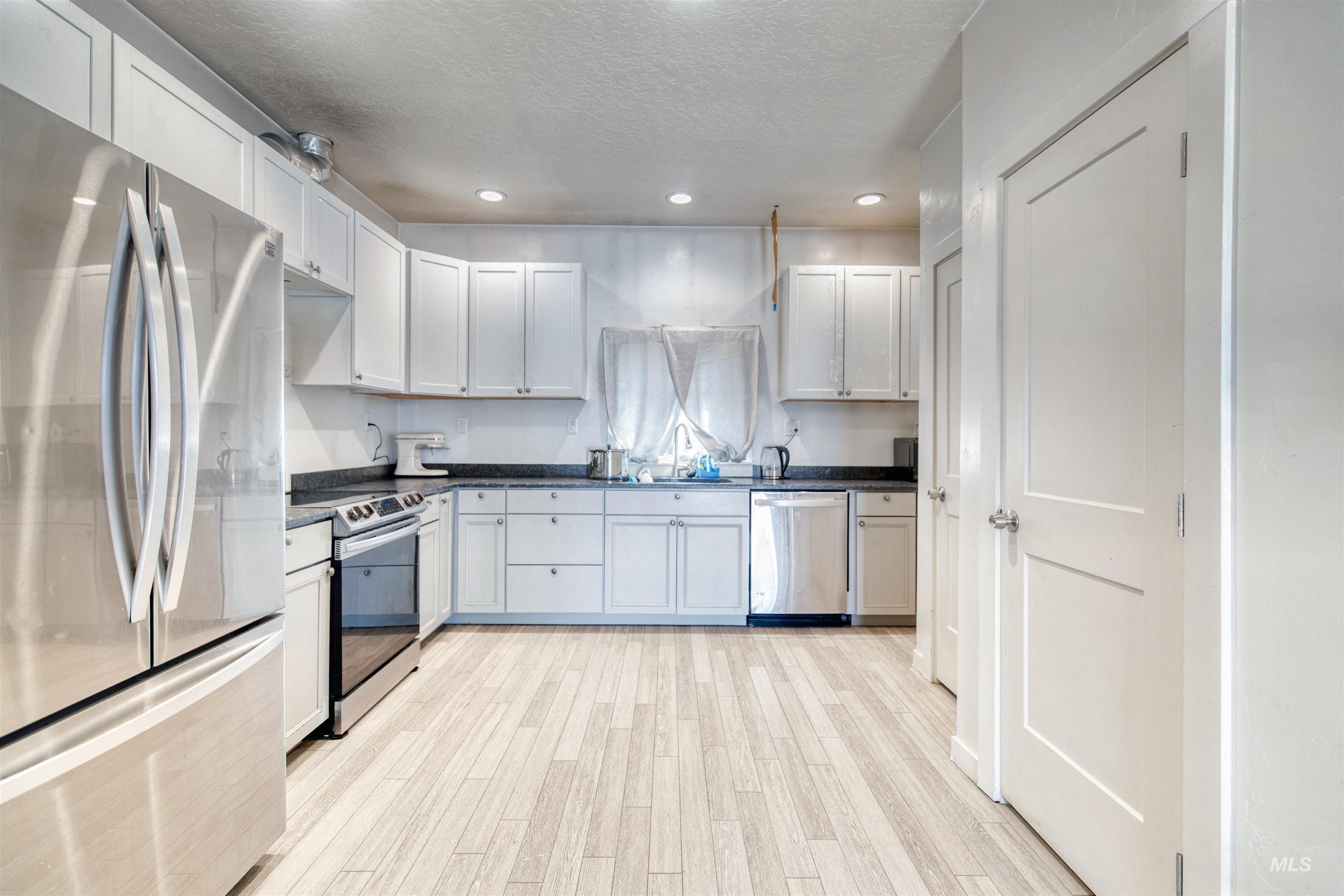112 East Main Street Nyssa, OR 97913 - Photo 17 of 43 Kitchen featuring stainless steel appliances, a textured ceiling, dark countertops, light wood-style flooring, and recessed lighting