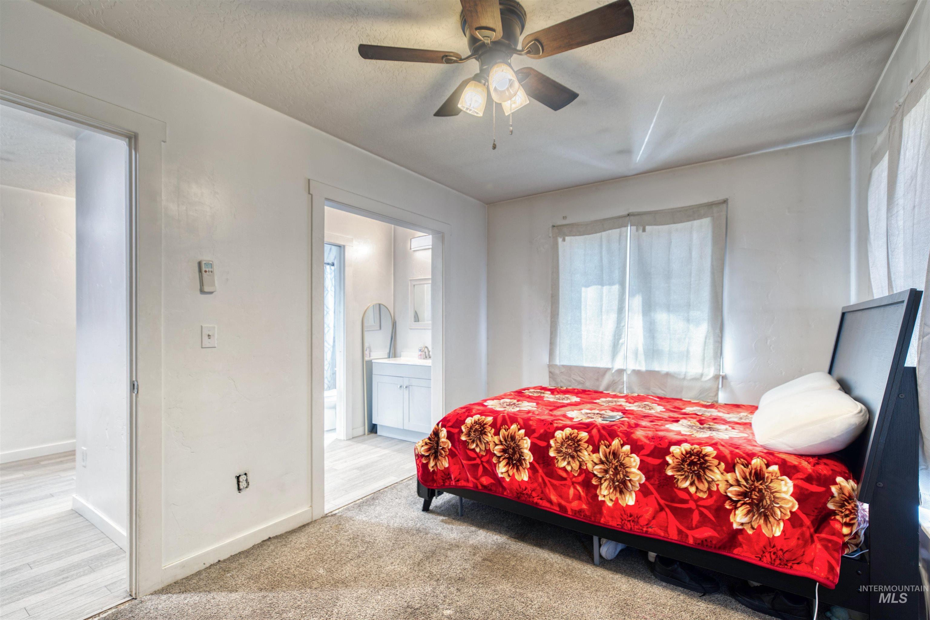 112 East Main Street Nyssa, OR 97913 - Photo 29 of 43 Bedroom with a textured ceiling, light colored carpet, multiple windows, connected bathroom, and ceiling fan