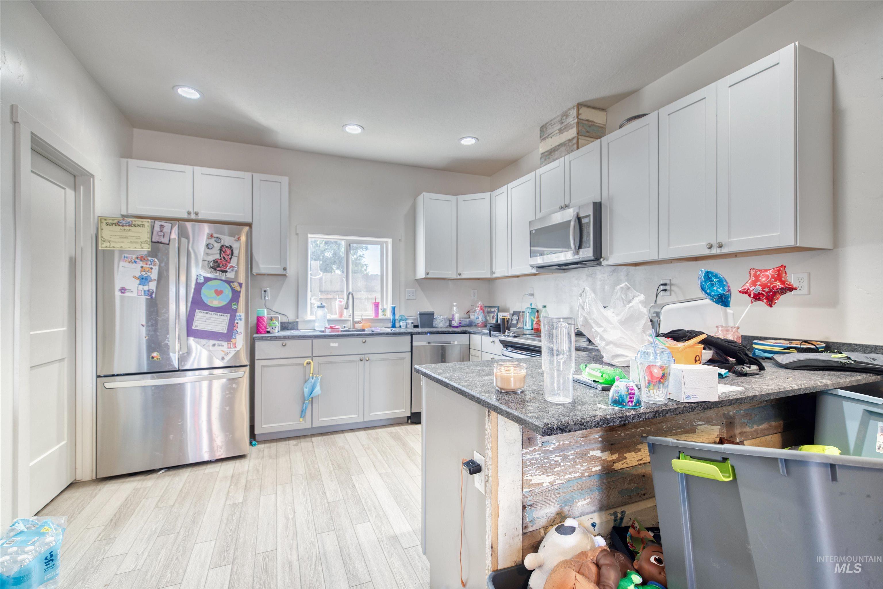 112 East Main Street Nyssa, OR 97913 - Photo 31 of 43 Kitchen featuring stainless steel appliances, light wood-type flooring, a peninsula, recessed lighting, and light stone countertops