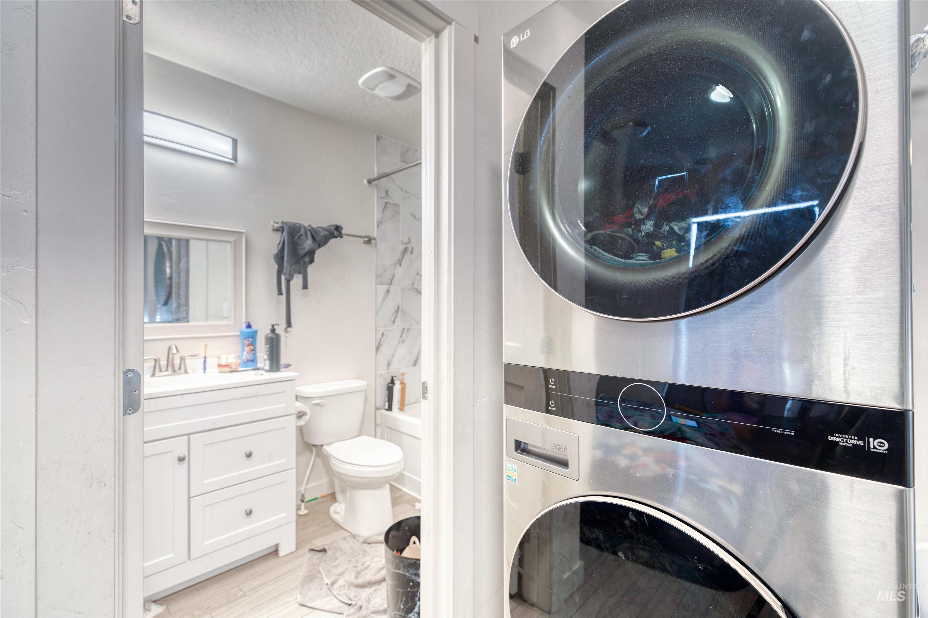 112 East Main Street Nyssa, OR 97913 - Photo 36 of 43 Full bathroom featuring stacked washing machine and dryer, vanity, a textured ceiling, bathtub / shower combination, and wood finished floors