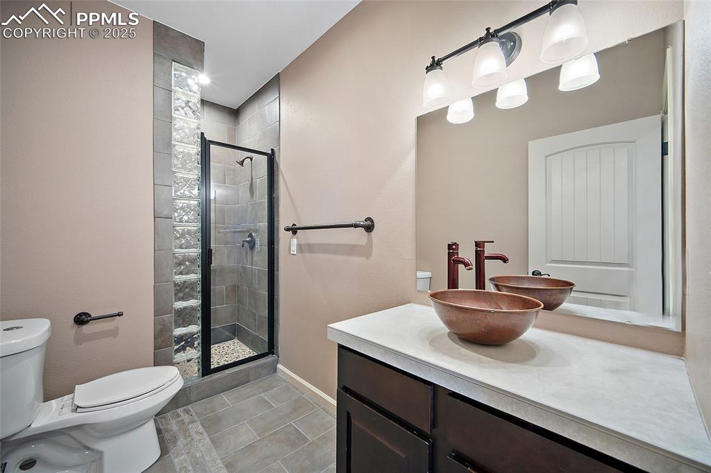 633 Tierra Verde Court Colorado Springs, CO 80904 - Photo 31 of 50 a bathroom with a granite countertop sink a toilet a mirror and shower