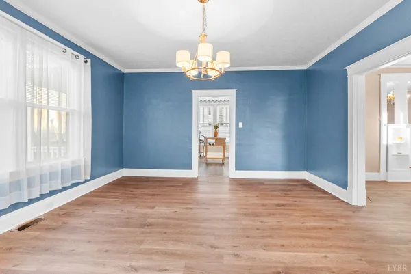 a view of an empty room with window and wooden floor
