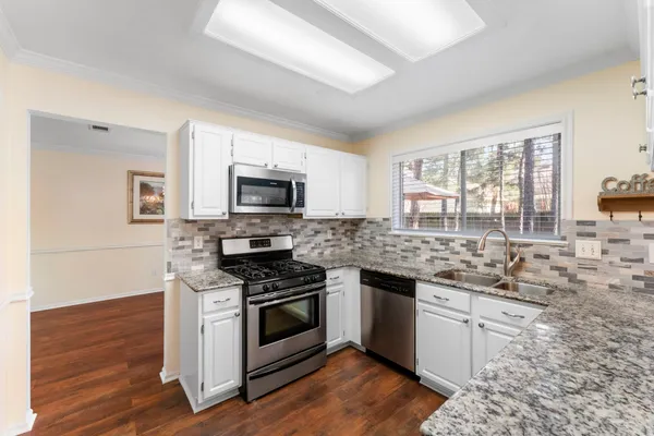 a kitchen with stainless steel appliances kitchen island granite countertop a stove and a sink