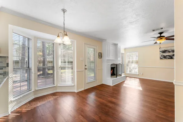 a view of a room with wooden floor fireplace and windows