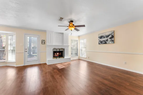 a view of an empty room with wooden floor and a fireplace