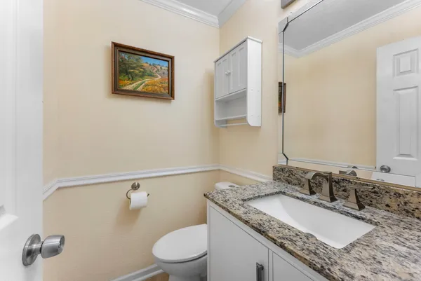 a bathroom with a granite countertop sink a mirror and a toilet