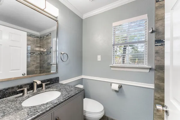 a bathroom with a granite countertop sink mirror vanity and toilet