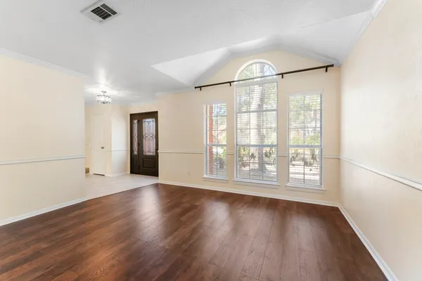 an empty room with wooden floor and windows