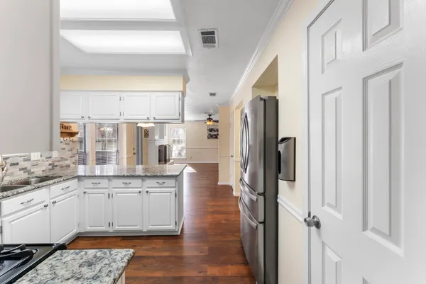 a large white kitchen with a granite countertop sink and a refrigerator