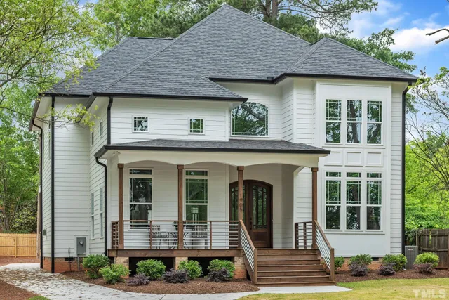 a view of a house with brick walls plants and large tree
