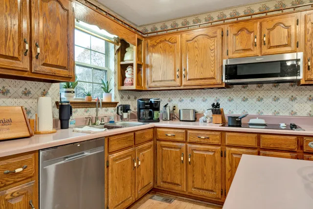 a kitchen with stainless steel appliances granite countertop a refrigerator a sink dishwasher and wooden cabinets with wooden floor