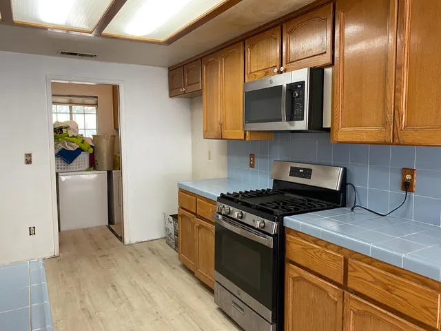 a kitchen with stainless steel appliances granite countertop a stove a sink and a microwave