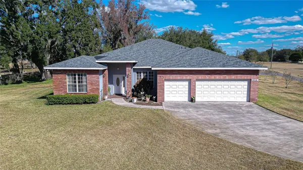 a view of a house with a yard and large tree