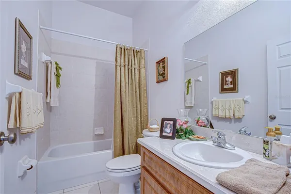a bathroom with a granite countertop sink a toilet a shower curtain and a bath tub