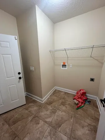 an empty room with a chandelier fan and a window