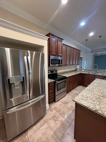 a kitchen with stainless steel appliances granite countertop a refrigerator a stove a sink and a microwave