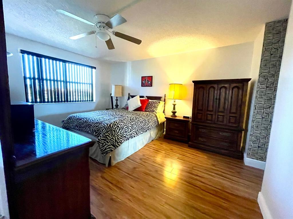 10444 Northwest 30th Court, Unit 409 Sunrise, FL 33322 - Photo 12 of 28 a bedroom with a bed and wooden floor