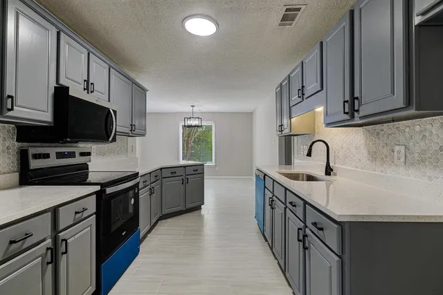 a kitchen with granite countertop a sink and steel appliances