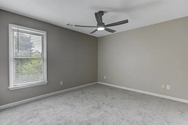 an empty room with a ceiling fan and a window