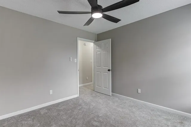 an empty room with a ceiling fan and window