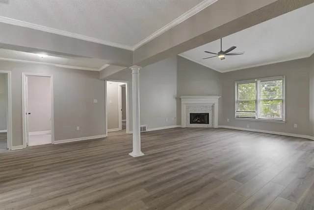 an empty room with wooden floor fireplace and windows