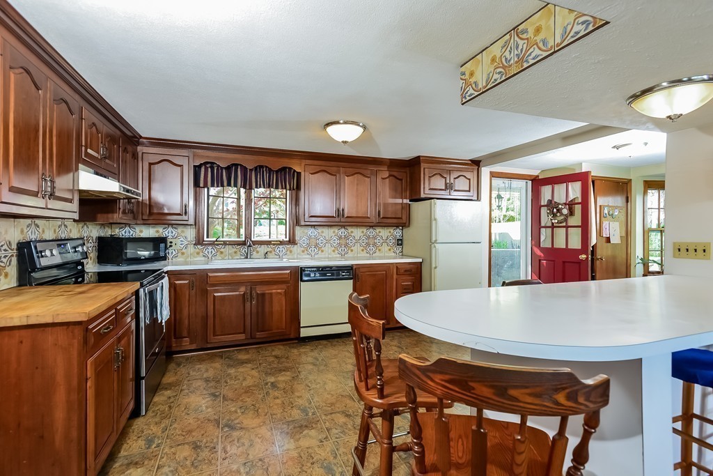 51 Pine Ridge Road Bourne, MA 02532 - Photo 9 of 25 a large kitchen with stainless steel appliances granite countertop a stove a refrigerator a oven a sink with a dining table and chairs