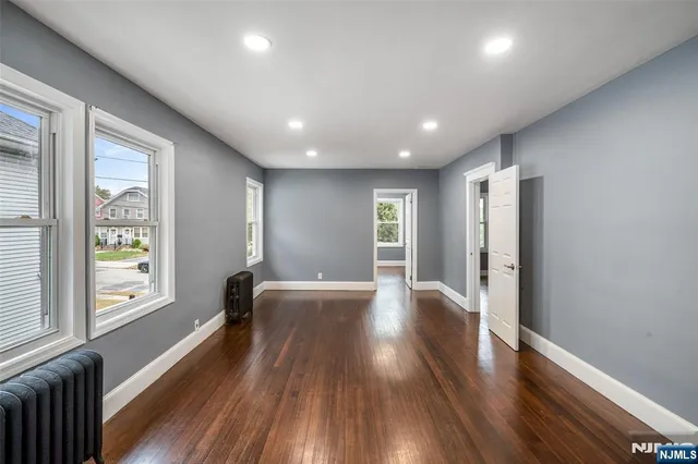 a view of a big room with wooden floor and windows