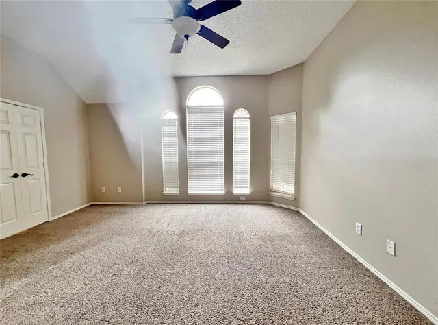 an empty room with windows and fan