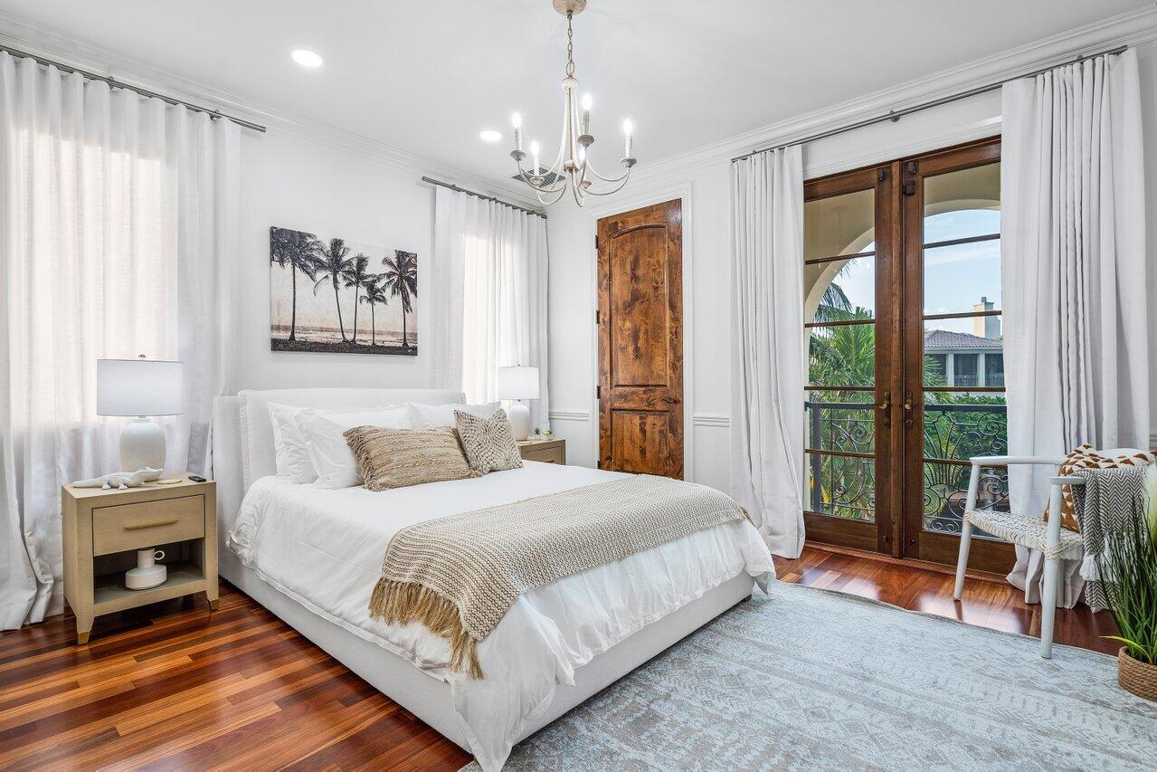 591 Phillips Drive Boca Raton, FL 33432 - Photo 46 of 90 a bedroom with a large bed and a chandelier