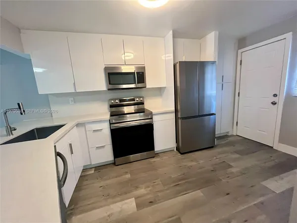 a kitchen with a refrigerator sink and white cabinets