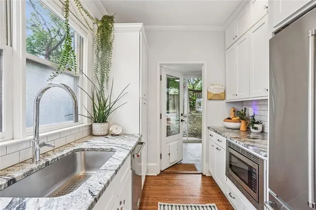 a kitchen with granite countertop stainless steel appliances a sink stove and cabinets