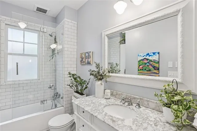 a bathroom with a granite countertop sink a toilet a large mirror and shower